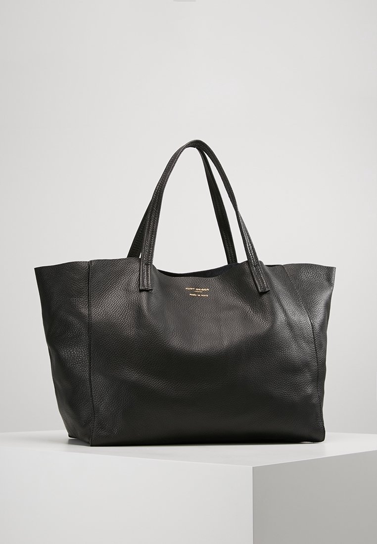 Svart läder tote-väska med en texturerad yta, två robusta handtag och subtil guldbranding på framsidan. Rektangulär form med öppen topp.