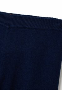 Tissu tricoté bleu foncé avec une manche côtelée au bord supérieur, montrant la texture et des points serrés.