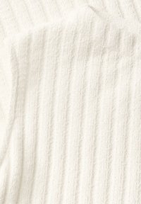 Hvidt tekstureret stof med vertikale ribber, blødt og fjollet, med en let fuzzy overflade, der giver et hyggeligt udseende.