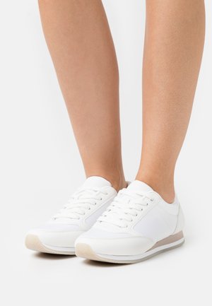 Weiße Sneakers aus glattem synthetischem Material, runde Zehenpartie, flache Sohle und Schnürdesign. Mit dezenten seitlichen Akzenten in Grau.
