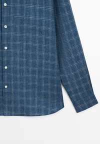 Niebieska koszula na długi rękaw z guzikiem, z białym wzorem w kratę i białymi guzikami, przedstawiona od połowy tułowia do końca rękawa na białym tle.