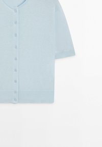 Světle modrý krátký rukáv kardigan na knoflíky s kulatým výstřihem a žebrovaným lemem a manžetami, zobrazený na bílém pozadí.