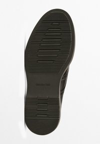 Semelle de chaussure noire avec des rainures à motifs pour l'adhérence, arborant le nom de la marque en relief "Massimo Dutti." Matériau en caoutchouc lisse et durable.