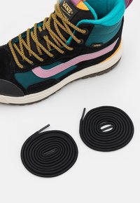 Zapatillas de caña alta con un upper de ante negro y acentos en azul y rosa, cordones con patrón y dos cordones negros enrollados a su lado.