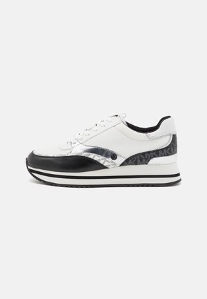 Sneaker bassa bianca e nera con allacciatura frontale, suola intermedia decorata e dettaglio con marchio sul tallone, mostrata di lato su sfondo semplice.