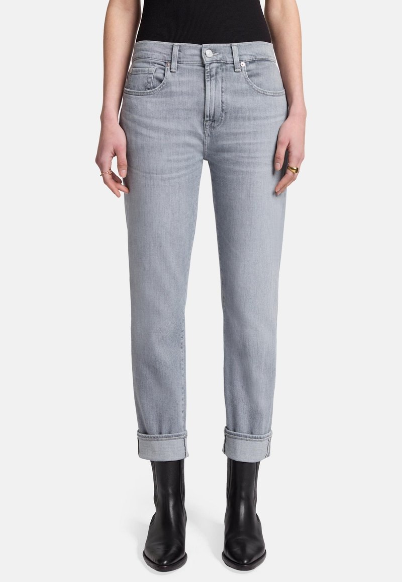 Jeans en denim gris clair avec une coupe straight, ourlets retroussés et poches avant. Portés avec des bottines noires.