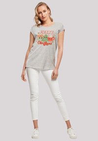 Grijze T-shirt met korte mouwen met een kleurrafische "Vrolijk Kerstfeest" opdruk met feestelijke motieven. Gecombineerd met witte strakke broek en sneakers.