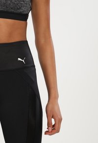 Leggings neri a vita alta con un pannello testurizzato, dotati di un piccolo logo Puma bianco sulla vita e un tessuto liscio e aderente.
