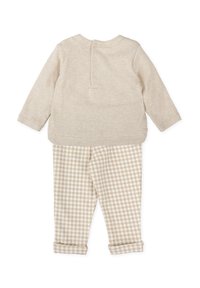 Top de manga larga beige con botones en la parte de atrás, combinado con pantalones de cuadro de gingham en beige y blanco, con dobladillos enrollados y una textura de tela suave.