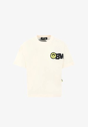 T-shirt color crema realizzata in cotone, con logo "OBW" nero e grafica di un sorriso giallo con zanne sul davanti. Maniche corte e collo rotondo.