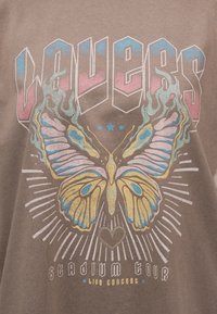 Νοσταλτική πεταλούδα με φλόγες, τρία μπλε αστέρια και γραφικό καρδιάς κάτω από το έντονο κείμενο "Volbeat" και την επιγραφή "stadium tour live concert".