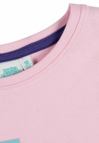 T-shirt in cotone rosa chiaro con scollatura rotonda, caratterizzato da un accento viola attorno al colletto e un'etichetta cucita vicino alla scollatura.