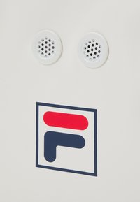 Superficie de producto blanca con dos ventilaciones circulares perforadas encima de un logo de colores. El logo incluye formas rojas y marinas dentro de un contorno cuadrado.