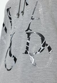 Felpa grigia con strass lucidi sul testo e un motivo animale in bianco e nero. Include dettagli con lacci argentati.
