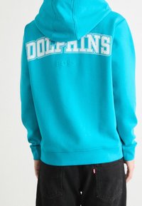 Turkos hoodie med en stor vit "DOLPHINS"-tryck och subtil "BOSS"-logga, med en känguruficka och ribbade muddar och nederkant.