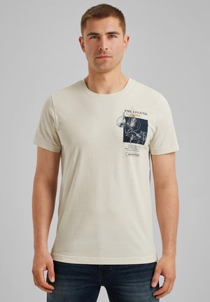 Crèmefarvet bomulds t-shirt med korte ærmer, der har et grafisk print i mørkeblå på venstre brystområde. Standard crew neck-design.