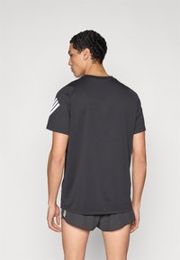 Must sportlikule must t-särk lühikeste varrukatega, ümara kaelusega. Vasakul õlal on kolm valget triipu. Sile kangapind.