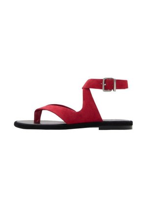 Sandalia de ante roja con diseño de tira entre los dedos, correa de tobillo con hebilla de metal y suela plana negra. Estilo simple y minimalista.