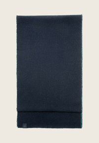 Bufanda de lana azul oscuro con una textura suave, con bordes con flecos y un diseño plegado. Se puede ver una pequeña etiqueta en una esquina.