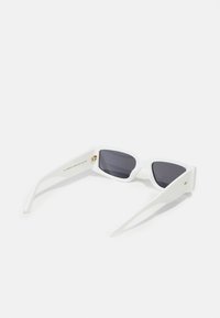 Gafas de sol blancas con montura angular, lentes oscuros y patillas rectas. Detalle dorado en el interior de la patilla. Acabado de plástico suave.