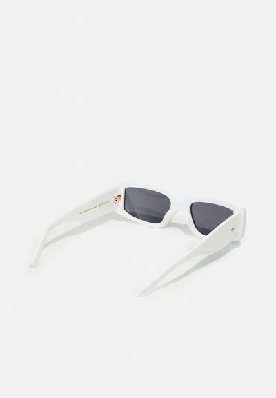 Weiße Sonnenbrille mit kantigen Rahmen, dunkel getönten Gläsern und geraden Bügeln. Goldakzent auf der Innenseite des Bügels. Glatte Kunststoffoberfläche.