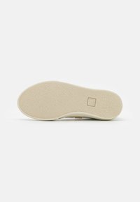 Suola di scarpa con superficie testurizzata e gommatta di colore bianco sporco. Presenta un design semplice con un piccolo logo impresso nella zona del tallone.