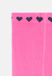 Calzini rosa brillante con un bordo a coste e piccoli cuori blu navy. Tessuto liscio, materiale lavorato a maglia e design senza cuciture.