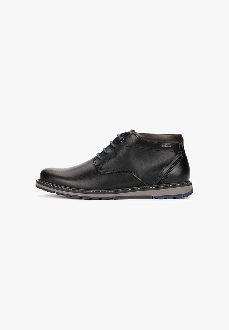Bottine en cuir noir avec lacets bleus, semelle grise et bleue, et étiquette de marque sur le côté, vue de l'extérieur.
