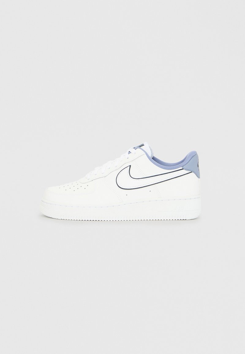 Fehér Nike Air Force 1 tornacipők, sima bőr felsőrésszel, világoskék részletekkel, lyuggatott orrésszel és vastag gumitalppal.