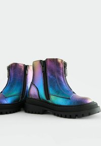 Stivaletti iridescenti con tomaia sintetica lucida, cerniere nere su entrambi i lati e una suola in gomma nera spessa con battistrada.