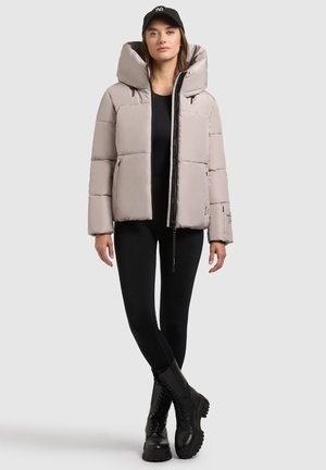 Hellgraue Steppjacke mit einer großen Kapuze, ausgestattet mit einem Reißverschluss vorne und zwei Seitentaschen, kombiniert mit schwarzen Leggings und Stiefeln.