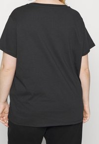 Czarna bawełniana koszulka z luźnym krojem, krótkimi rękawami i zaokrąglonym dekoltem. Szwy na plecach oraz subtelne logo na końcu.
