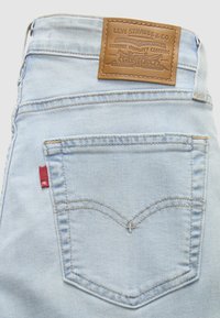 Πίσω τσέπη από ανοιχτό μπλε τζιν Levi's με χαρακτηριστική ραφή arcuate, κόκκινο ταμπελάκι και καφέ δερμάτινο λογότυπο στη ζώνη της μέσης.