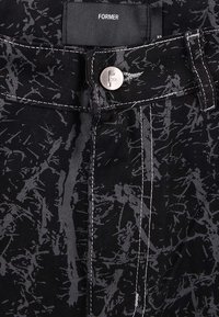 Μαύρο τζιν με υφασμένο σχέδιο που διαθέτει γκρι αφηρημένα μοτίβα, κούμπωμα με ασημένιο κουμπί και αντίθετη λευκή ραφή.