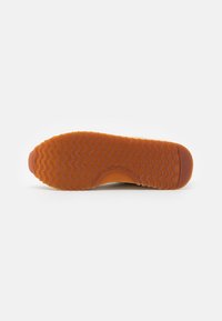 Gummisohlen mit einem wellenförmigen Profil. Farbe ist orange-braun. Verfügt über eine glatte Oberfläche und ein gerundetes Zehendesign. Größe ist mit 37 gekennzeichnet.
