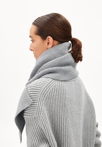 Écharpe grise en tricot avec une texture côtelée large, drapée autour du cou. Le design présente un large col replié et une finition douce.