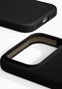 Czarny etui na telefon o matowym wykończeniu i gładkiej teksturze, z widoczną brązową podszewką wewnętrzną. Posiada wycięcia na przyciski i porty.