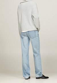Lyseblå lige ben jeans lavet af denim, med et klassisk fem-lomme design og let falmede, parret med en tekstureret grå sweater.