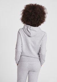 Grå huvtröja i mjukt, texturerat tyg. Har en känguruficka samt ribbade ärmslut och nederkant. Stylad med matchande byxor.