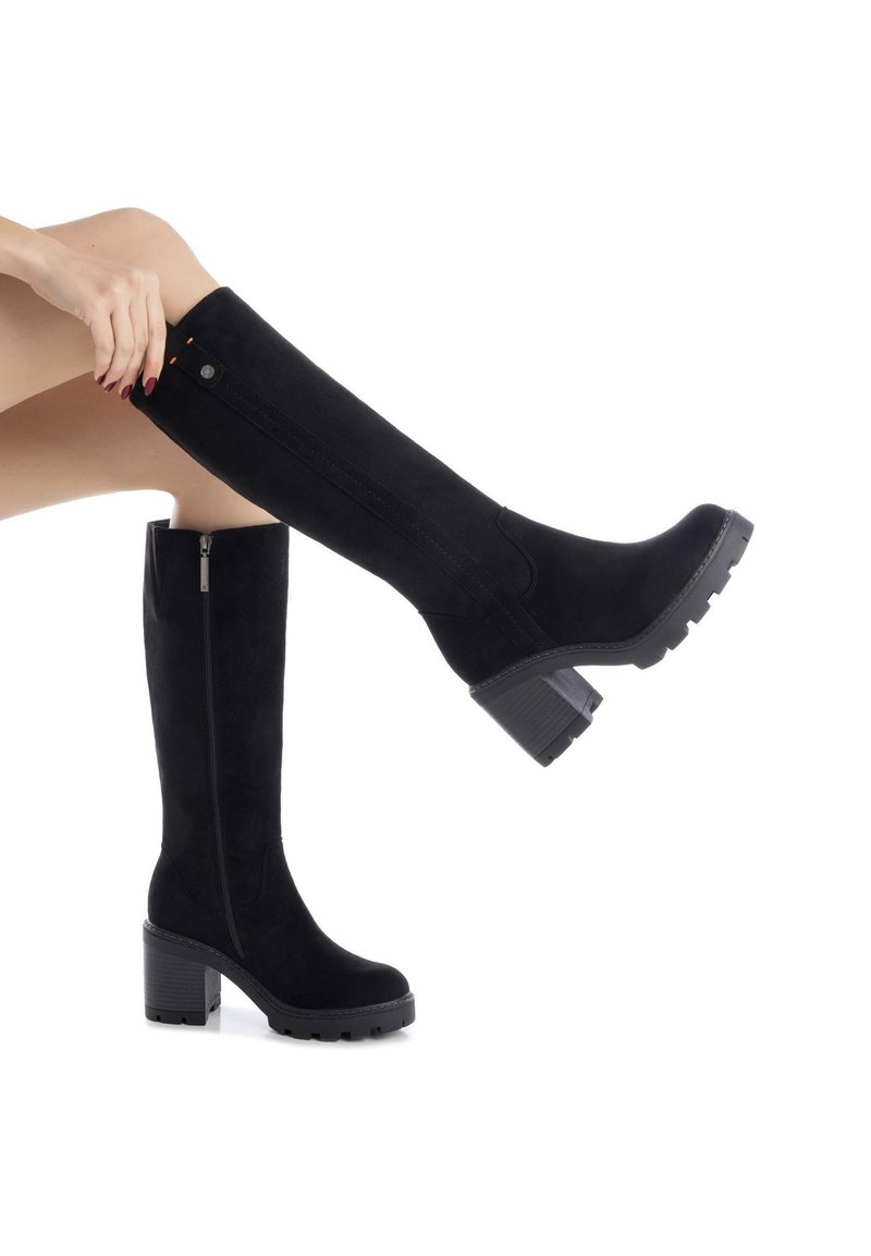 Stivali neri al ginocchio realizzati in morbida suede, con tacco largo, zip laterale e cuciture decorative per texture e dettaglio.