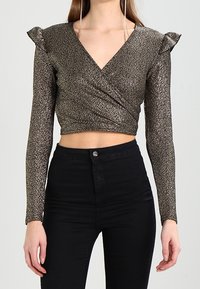 Schwarzes und goldenes langärmliges Wickeloberteil mit tiefem V-Ausschnitt und gerafften Schulterakzenten, aus einem glitzernden, strukturierten Stoff.
