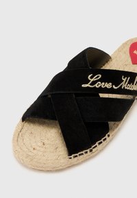 Μαύρες σουέτ σανδάλια με διαγώνιες λωρίδες, διακοσμημένα με κεντημά "Love Madrid" σε χρυσό. Σόλα από τζούτ με υφαντή υφή και ραμμένα διακοσμητικά στοιχεία.