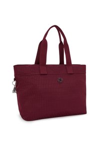 Maroon tote bag with textured fabric, featuring dual handles, a round logo patch, and a charm accent on the zipper pull.