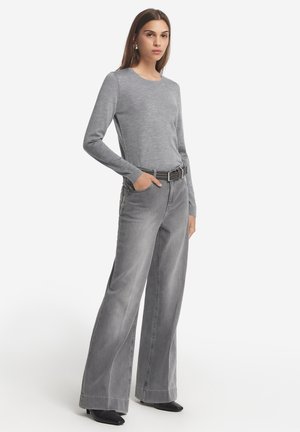 Szary top z długim rękawem w połączeniu z szarymi spodniami typu wide-leg z wysokim stanem. Stylizacja wyróżnia się teksturowanym materiałem oraz czarnym paskiem z metalową klamrą.