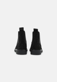 Stivaletti alla caviglia in camoscio nero con inserti elastici ai lati, tacco strutturato e suola in gomma. Design semplice con linguette per facilitarne la calzata.