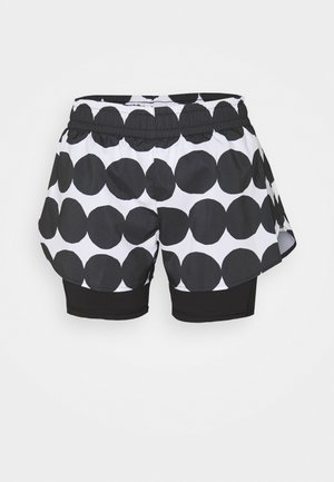 White athletic shorts with large black polka dots over fitted black compression shorts, elastic waistband, curved hem.