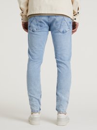 Svetlo modri kavbojki s slim fit krojem, z dvema zadnjima žepe, subtilnim zbledelostjo in rebrastimi manšeti. V kombinaciji z belimi supergami.