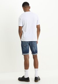 White short-sleeve t-shirt, blue denim shorts with rolled cuffs, black lace-up shoes, and white athletic socks. Simple design, casual fit.