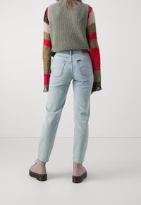 Ljust blå raka jeans med medelhög midja, parat med en flerfärgad, texturerad oversized tröja och grå snörkängor.