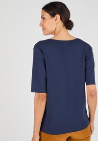 Top de manga corta azul marino con escote redondo y textura acanalada. Presenta un corte relajado y un dobladillo curvado en la parte posterior.